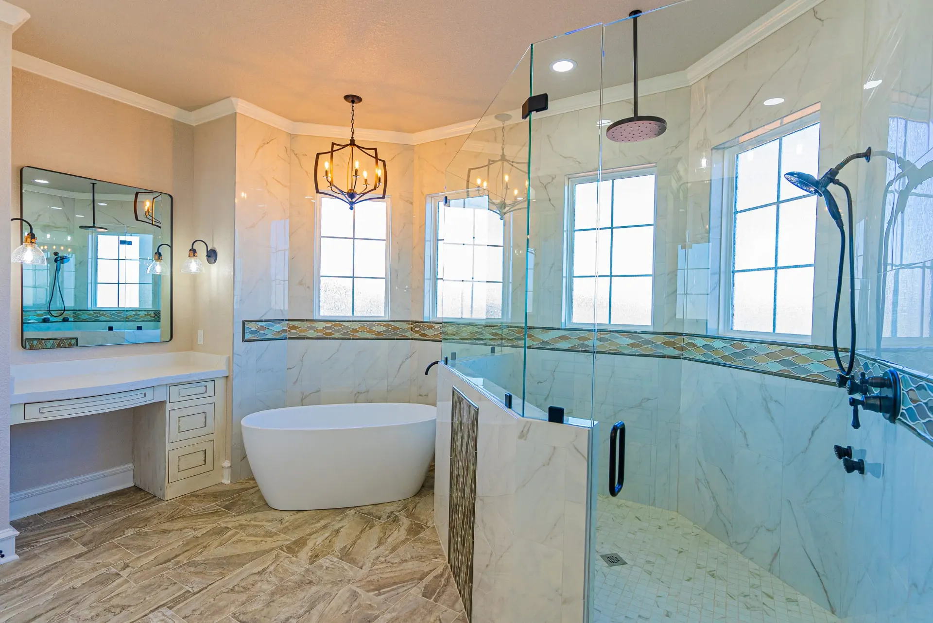 Primary bath at 1602 NW 12th St with freestanding tub, marble tile, glass-enclosed shower and iron chandelier
