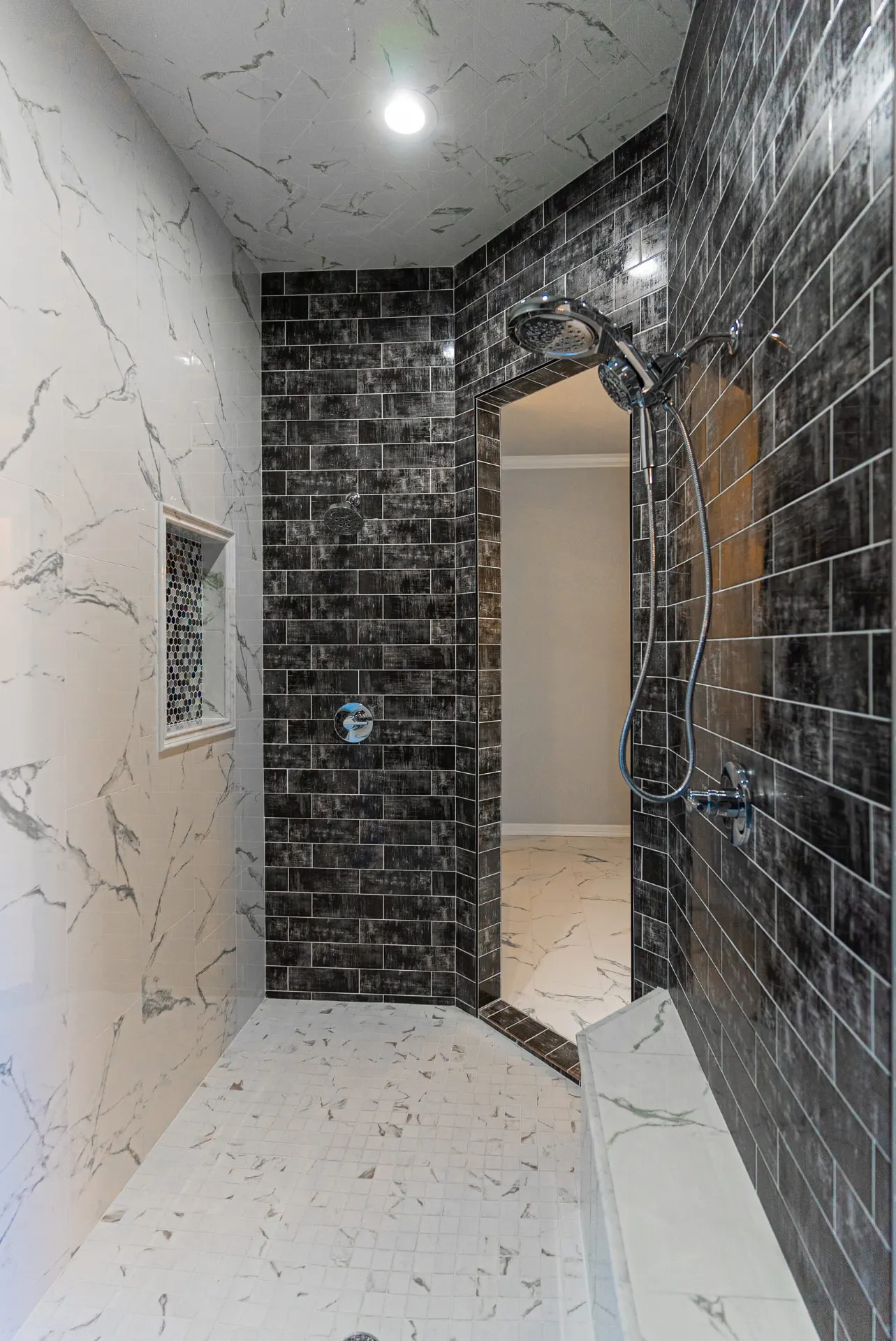 Walk-in shower at 1511 NW 12th St with dark glazed brick tile, dual shower heads and mosaic niche