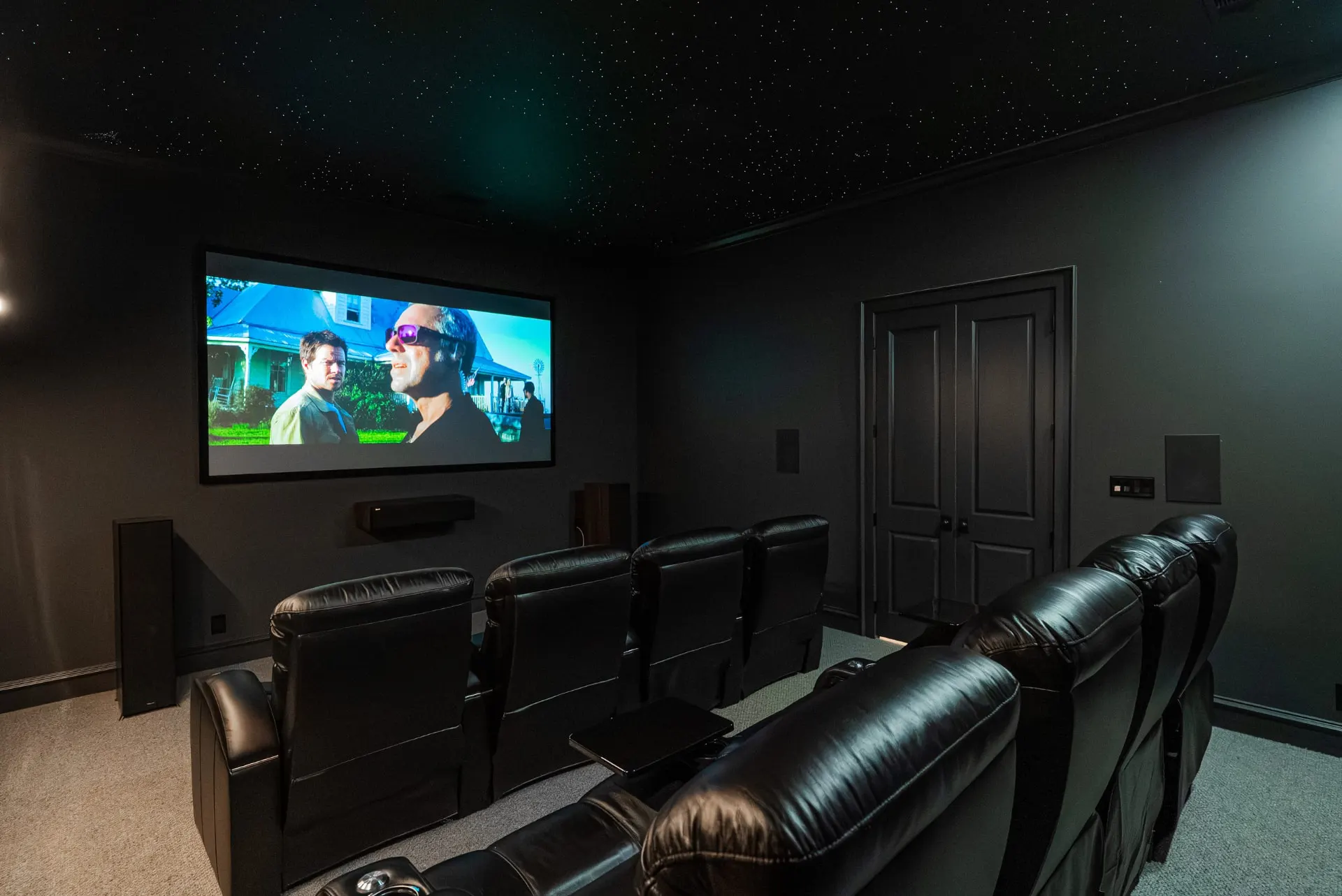 Side view of the tiered theater room at 1610 NW Eliam Dr with recliners and dark double doors