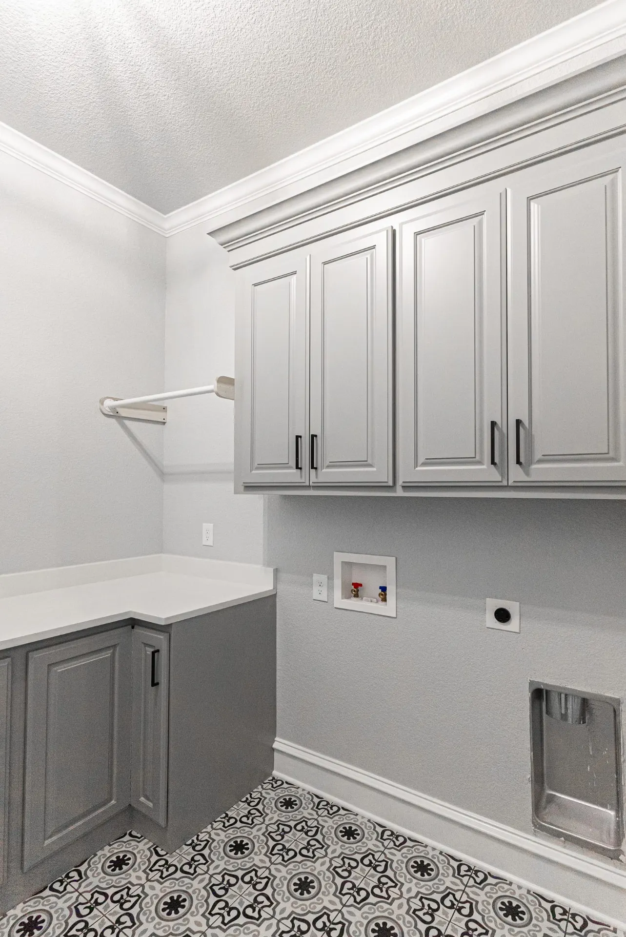 Laundry room at 1511 NW 12th St with gray cabinetry, white counters, wall-mounted ironing bar and patterned tile floor