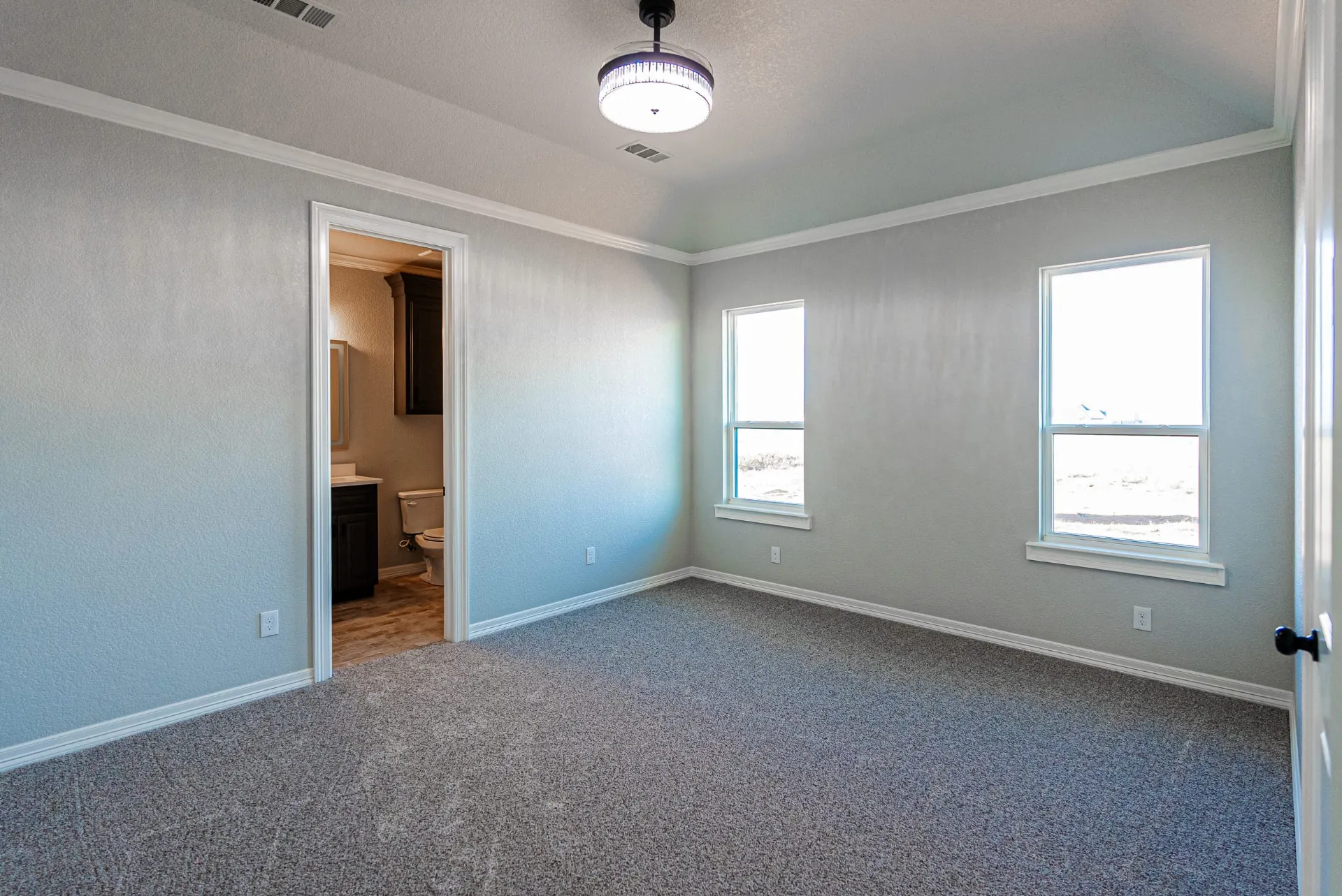 Carpeted bedroom at 1511 NW 12th St with twin windows and a doorway to the private bath