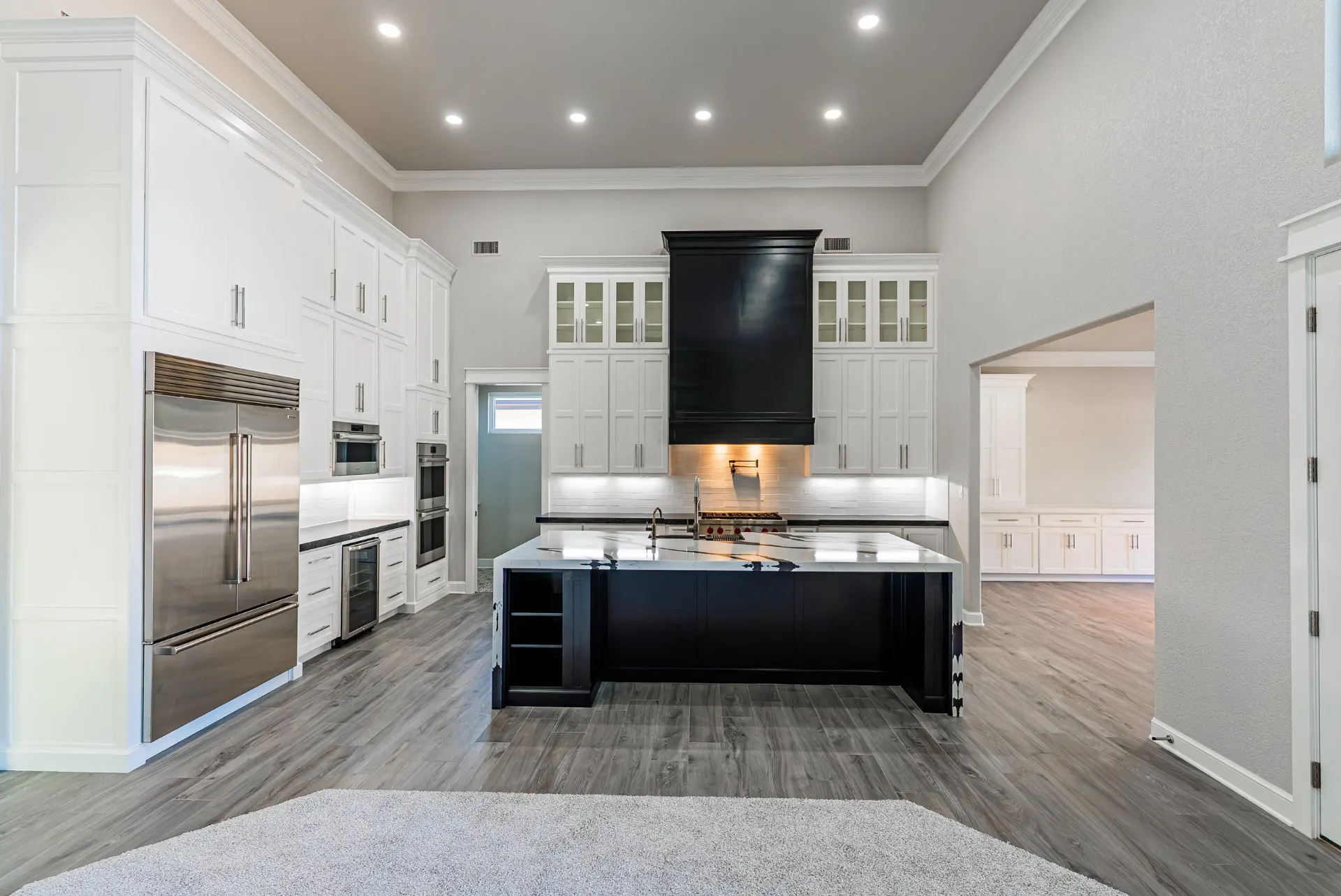 Kitchen at 27 Santiago Mission Dr with a built-in stainless refrigerator, double wall ovens and a dark island under a waterfall quartz top
