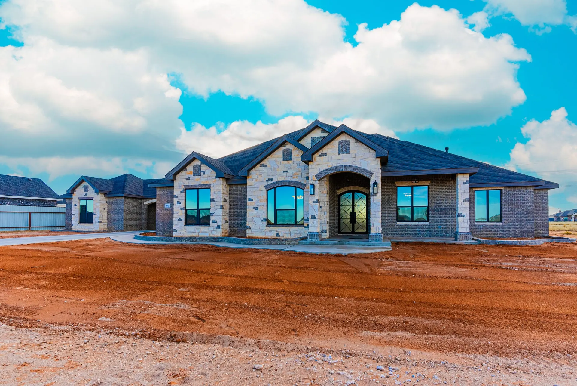 Stone-and-brick front elevation with arched iron entry, gabled roofline and curved drive at 1511 NW 12th St