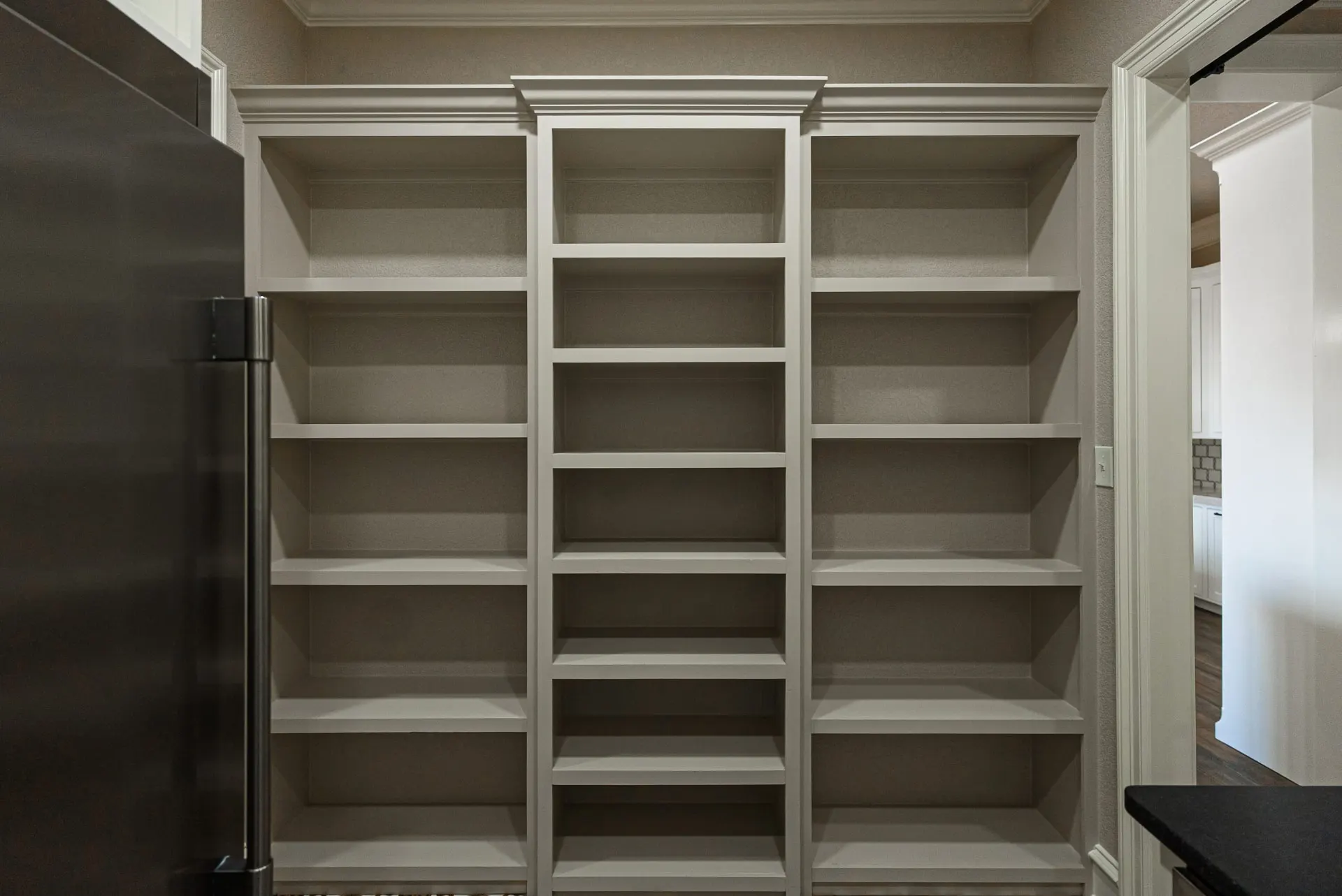 Butler's pantry shelving at 1602 NW 12th St with taupe built-ins flanking a paneled refrigerator wall