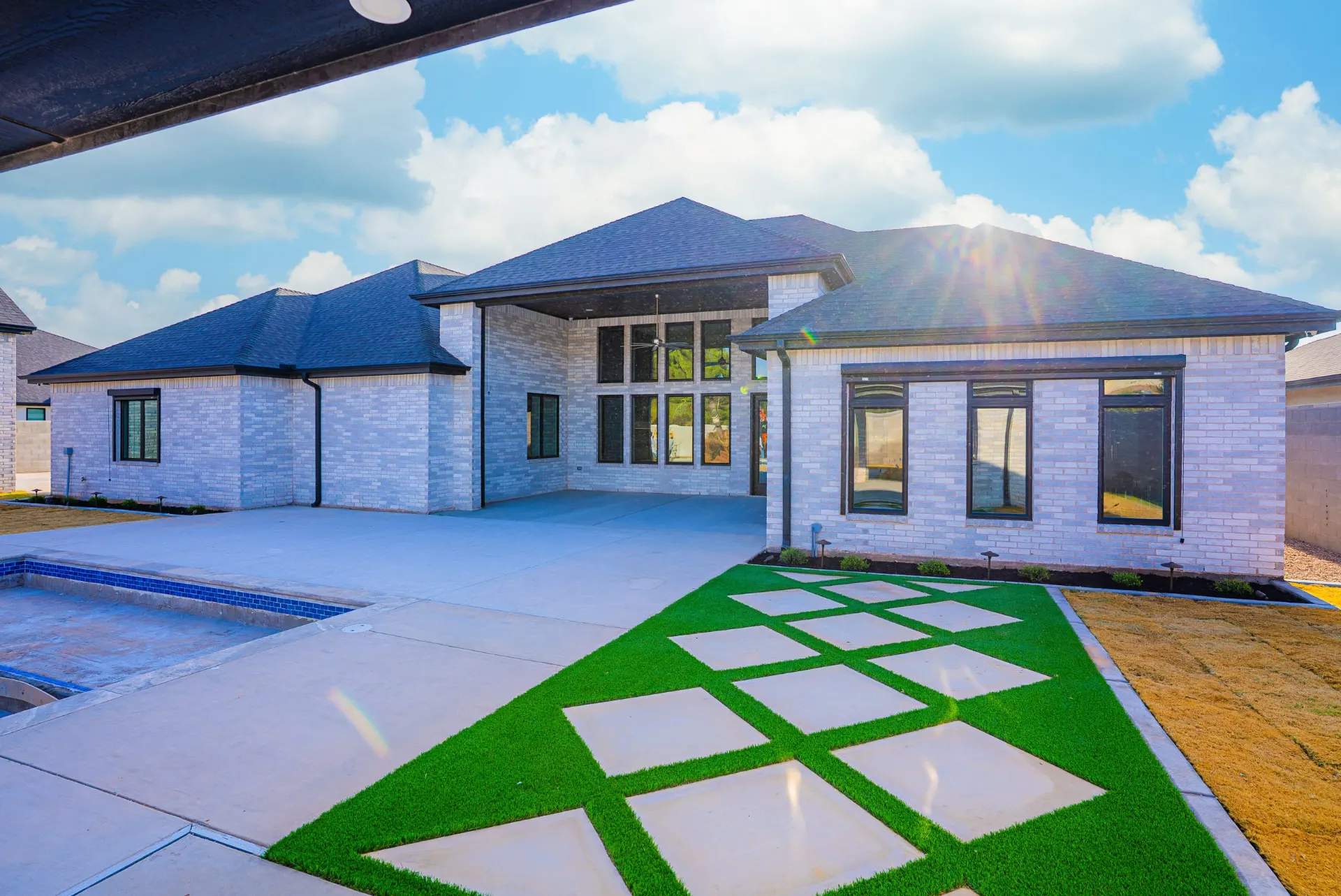 Backyard at 27 Santiago Mission Dr with an in-ground pool, covered porch and geometric concrete pavers set in turf