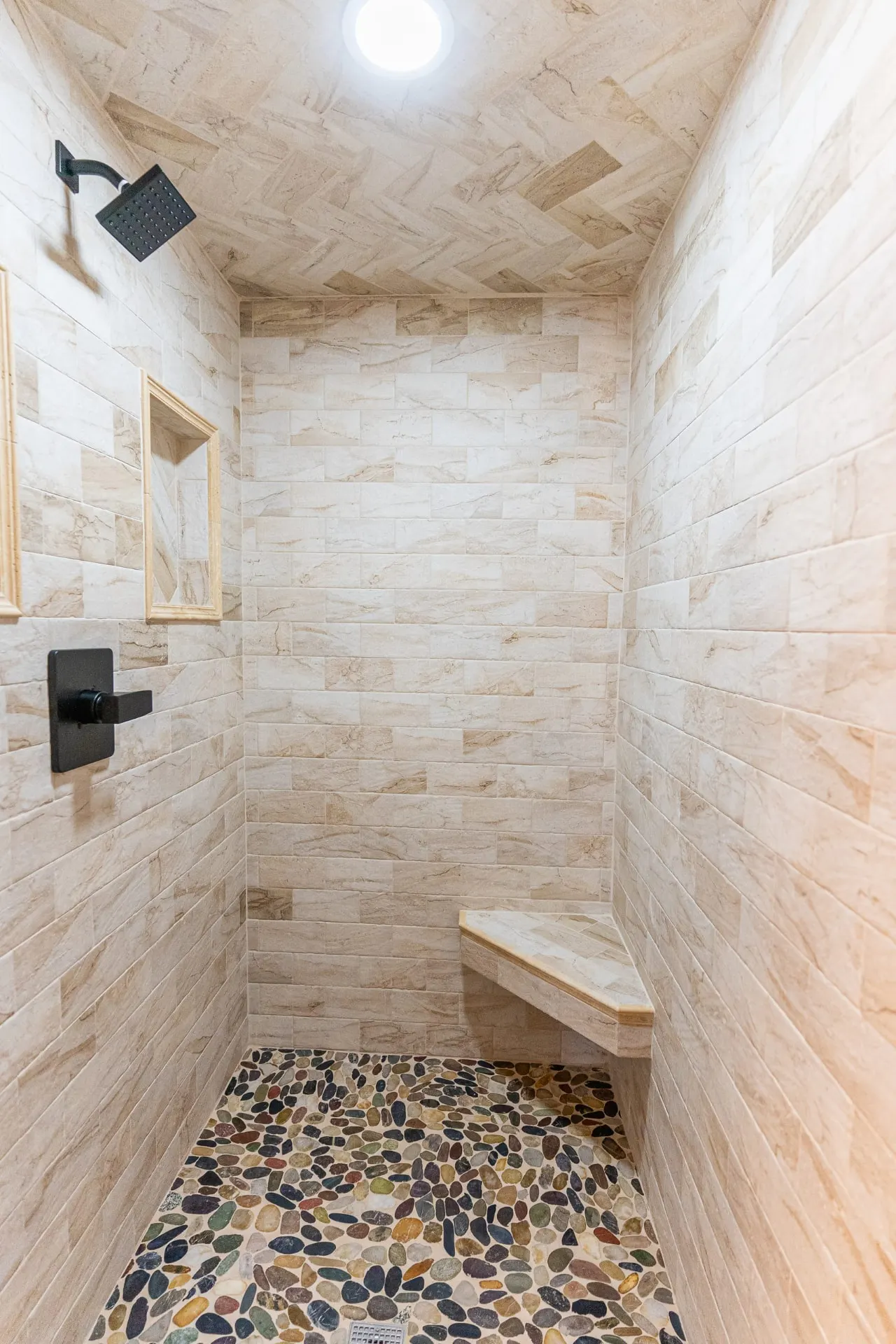 Walk-in shower at 718 K Ave with beige stacked-stone walls, a herringbone ceiling, corner bench, niche and pebble floor