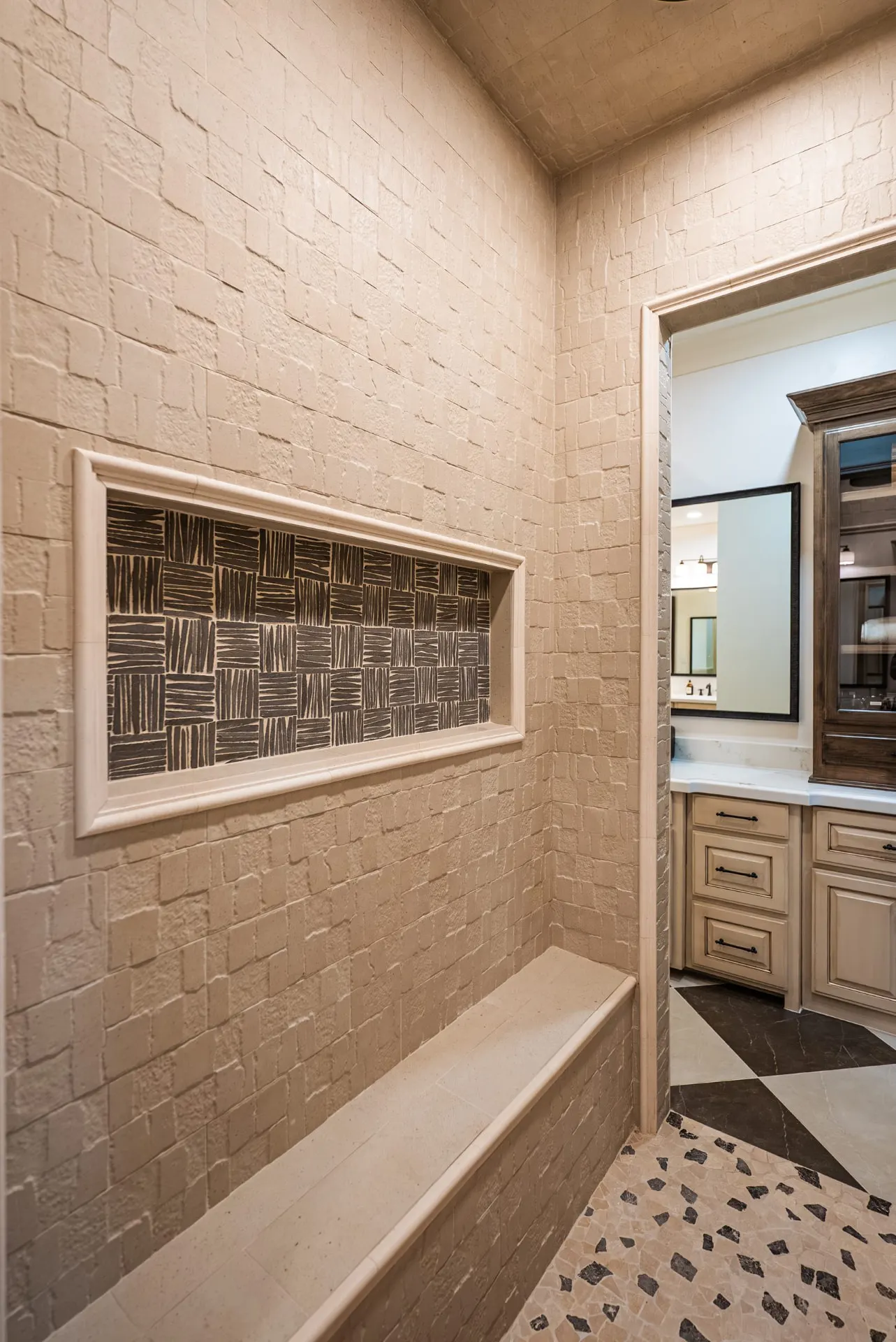 Walk-in shower at 1610 NW Eliam Dr with chiseled stone walls, long bench and woven-tile niche