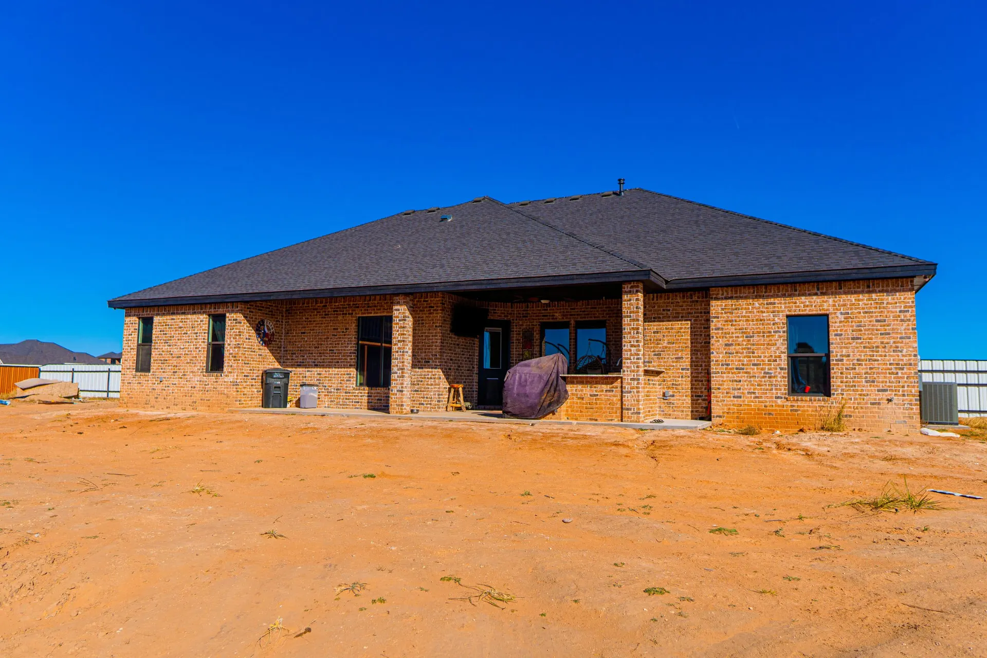 Rear elevation in red brick with a dark hip roof and a deep covered patio at 8821 Shawn Dr