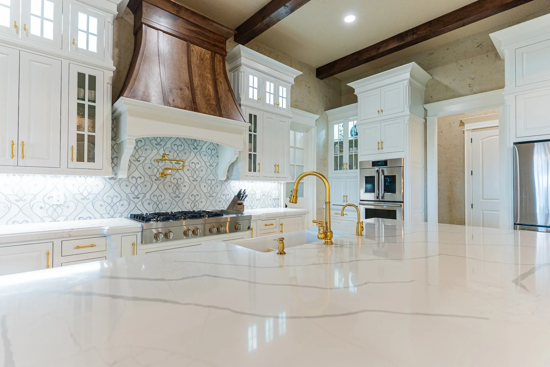 Kitchen island, cabinetry and wood range hood at The Flores Estate