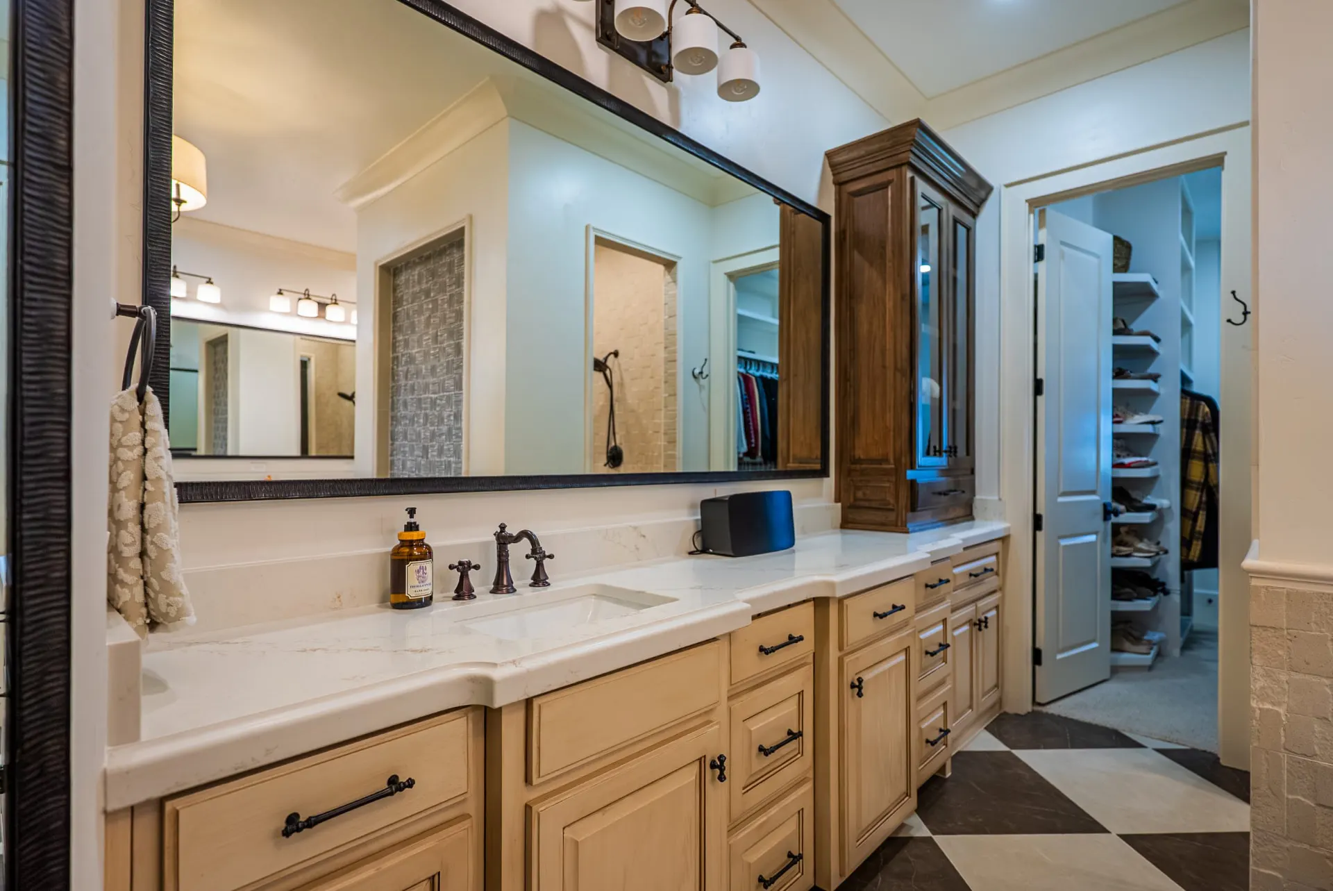 Primary bath vanity at 1610 NW Eliam Dr with glazed cabinetry, quartz top and glass-front tower opening to the closet