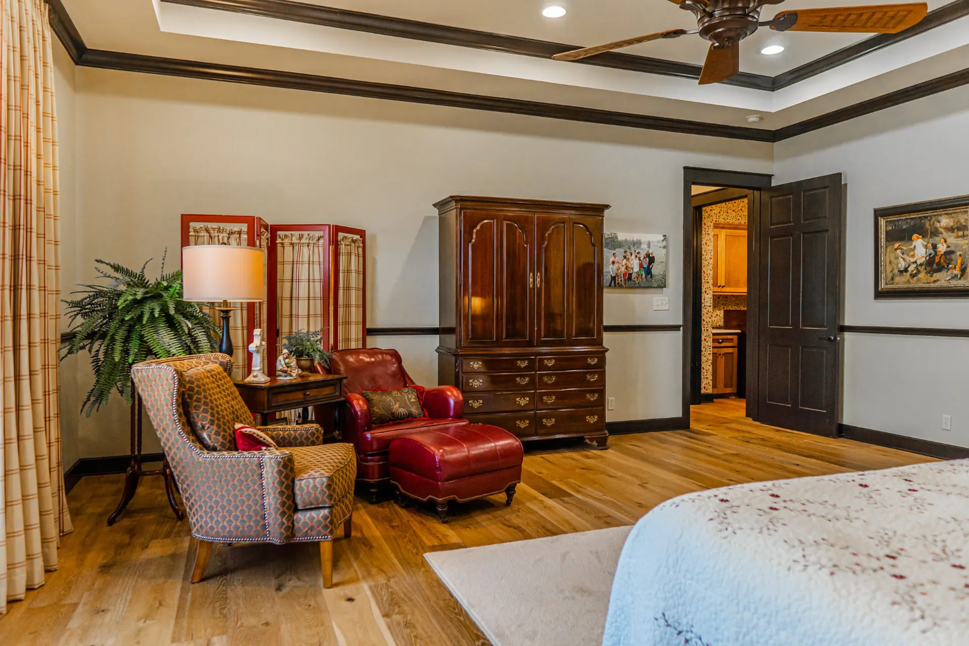 Primary suite at the Wraparound Porch Home with a reading corner, armoire and doorway to the bath